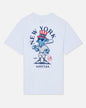 White short-sleeve t-shirt with a large graphic on the front featuring a blue cartoon goat in a baseball uniform, a red and white top hat, and the text 'NEW YORK' and 'GOAT USA'.#color_white
