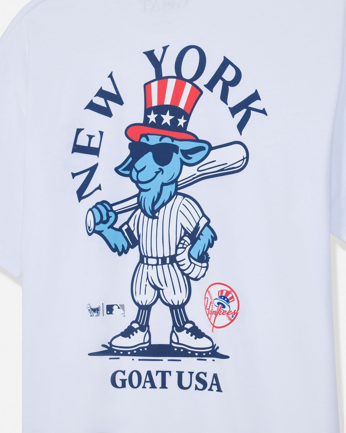 White short-sleeve t-shirt featuring a blue cartoon goat mascot in a baseball uniform with a red, white, and blue top hat. The graphic includes the text 'NEW YORK' arched above and 'GOAT USA' below, with MLB and New York Yankees logos near the bottom.#color_white