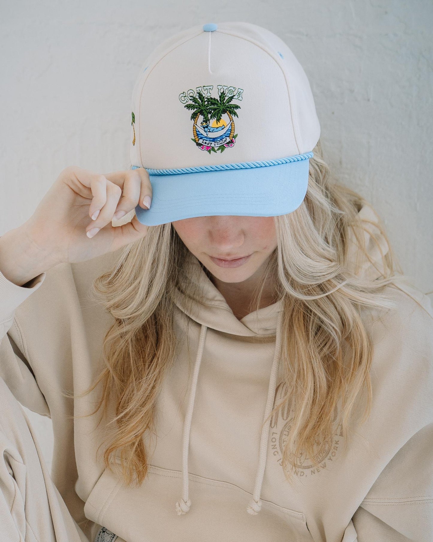 Girl wearing cream hat with blue rope and brim.