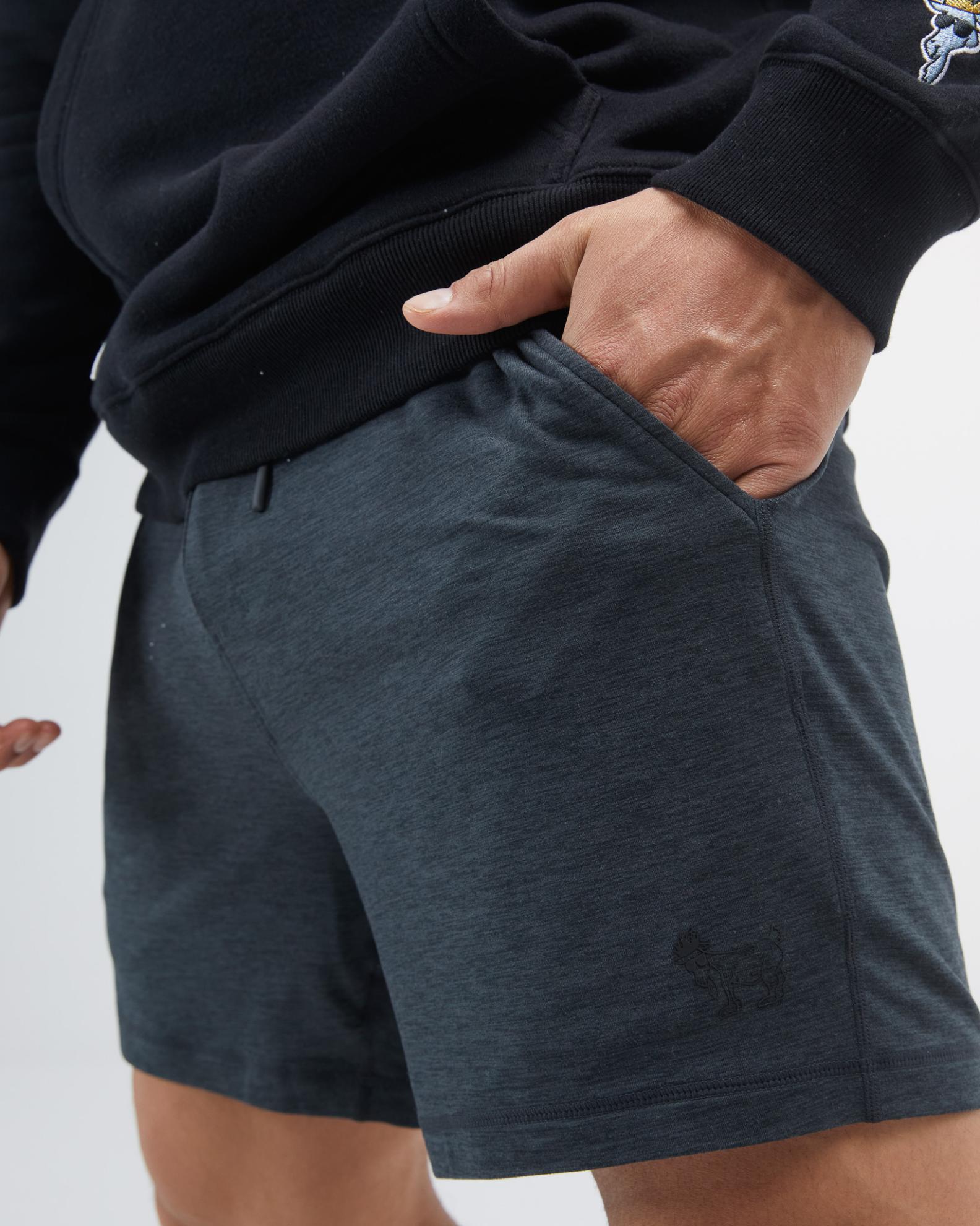 Person wearing dark gray shorts with a small logo on a light gray background#color_space-dye-black