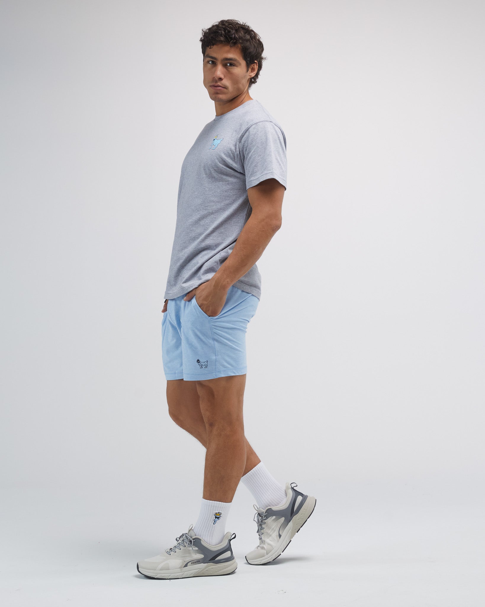 Man wearing a gray t-shirt, light blue shorts, and white sneakers on a plain background#color_carolina-blue