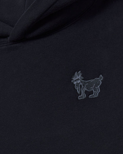 Black fabric with a small embroidered logo of a goat on a dark background#color_black