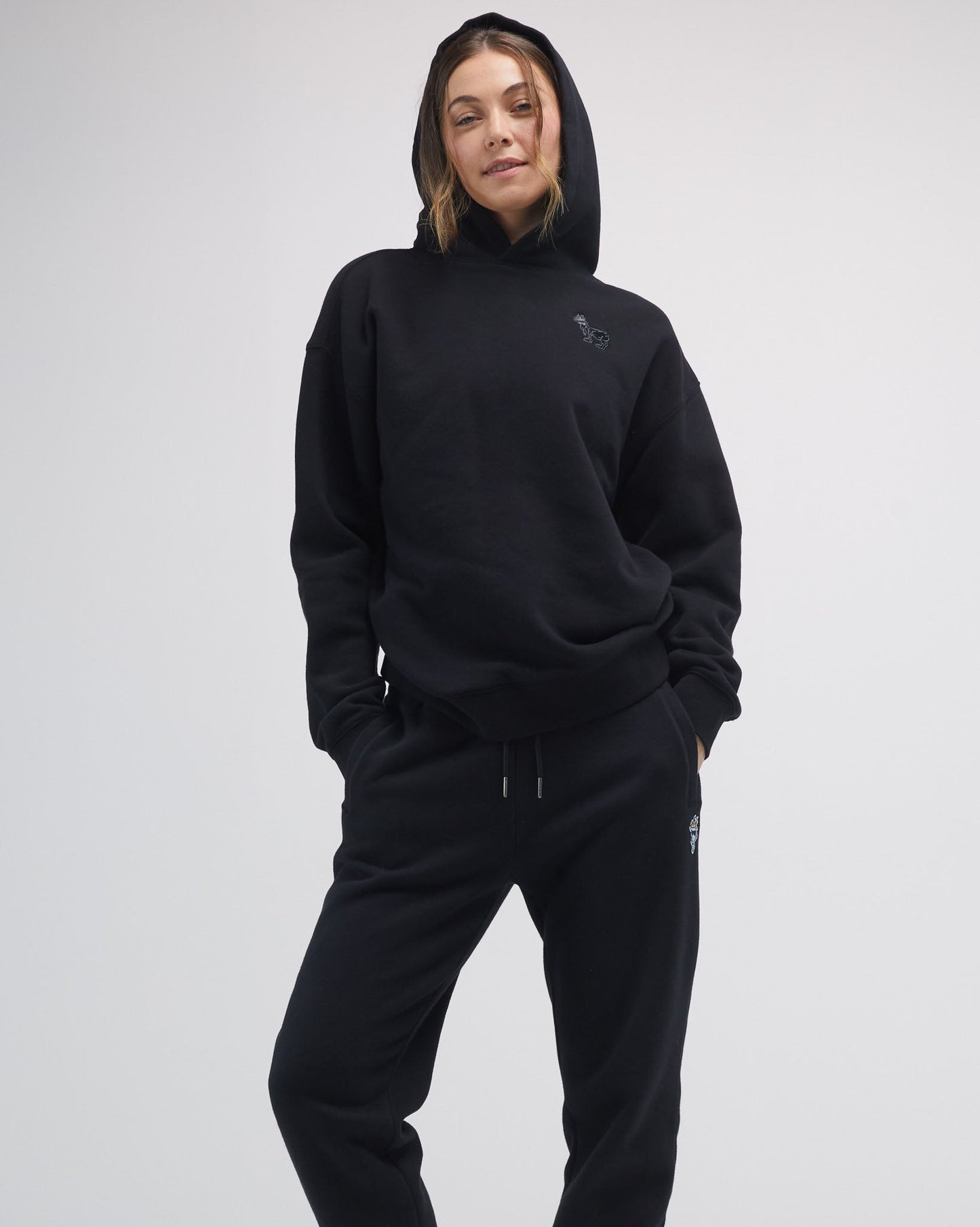 Person wearing a black hoodie and pants on a white background#color_black