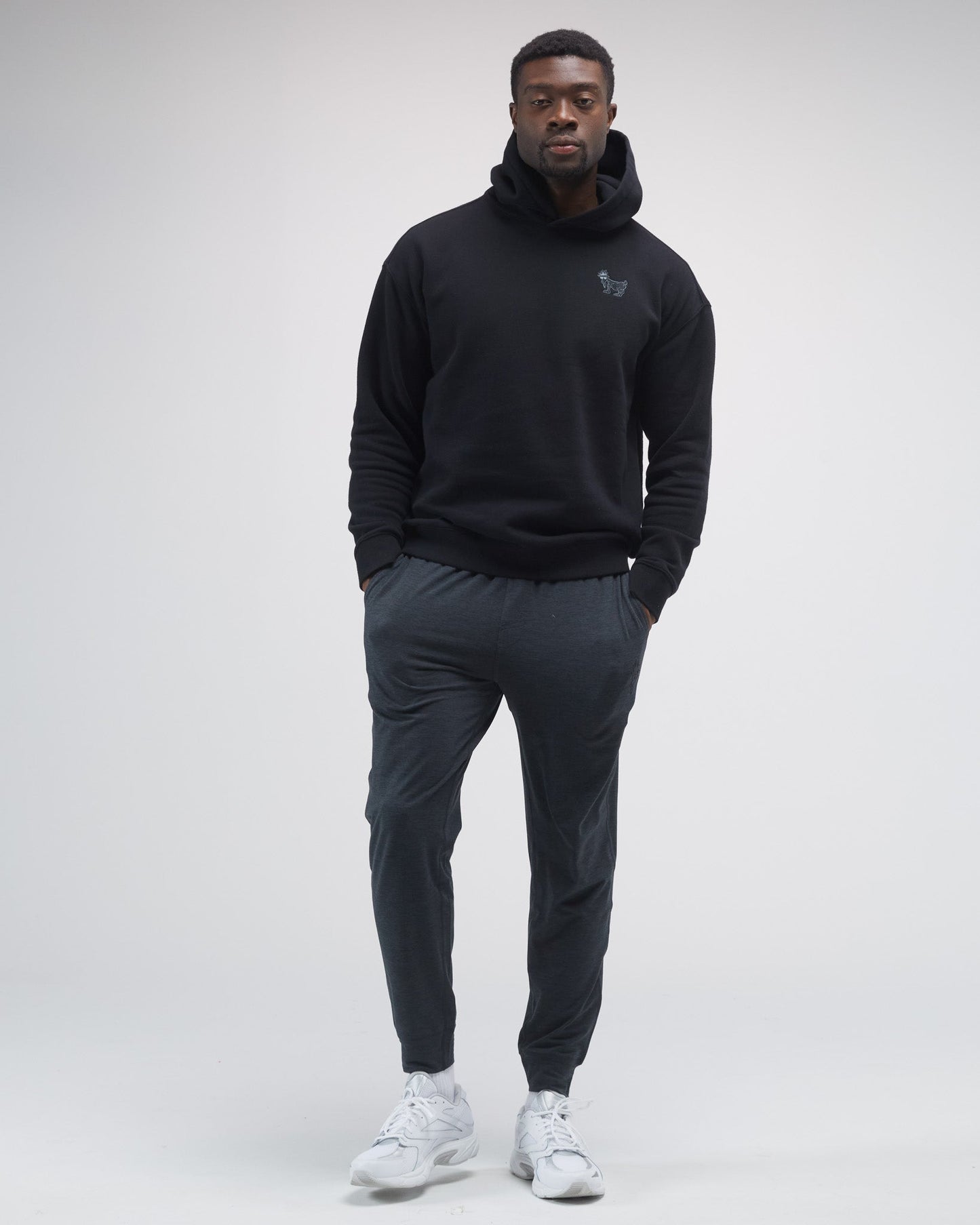 Person wearing a black hoodie and dark pants on a white background#color_black