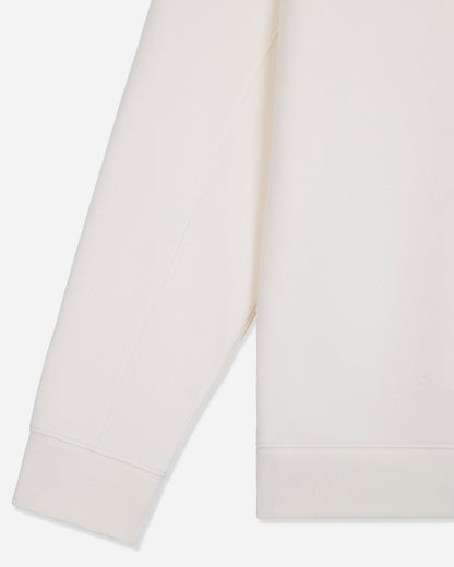 Close-up of a light cream or off-white fabric garment, showing part of a sleeve and the hem with ribbed cuffs and hem.#color_bone