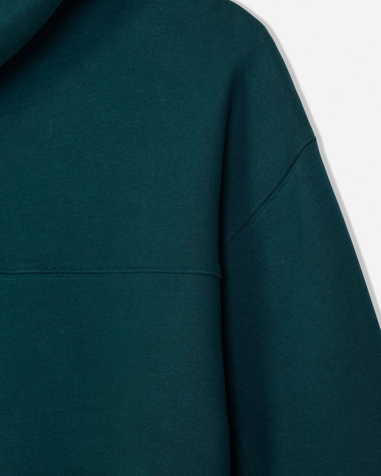 Close-up of a dark teal-green hooded sweatshirt showing the fabric texture, hood edge, and shoulder seam against a plain light background.#color_sage