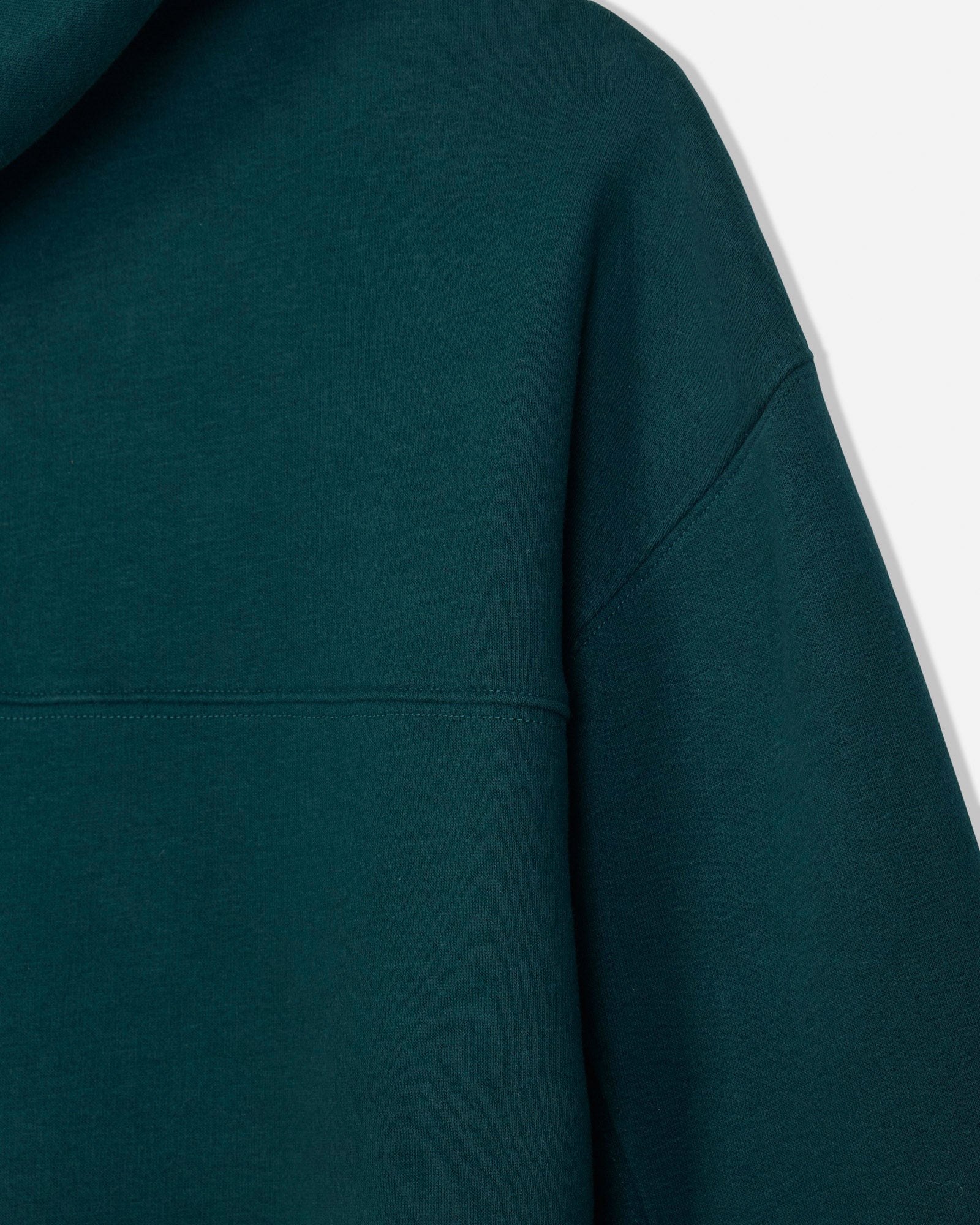 Close-up of a dark teal-green hooded sweatshirt showing the fabric texture, hood edge, and shoulder seam against a plain light background.#color_sage