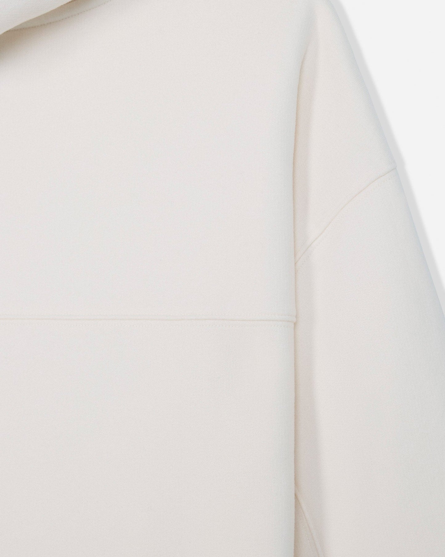 Close-up of a light cream or off-white garment showing the smooth fabric texture and a seam detail.#color_bone