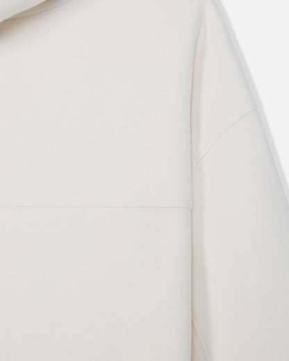 Close-up of a light cream or off-white garment showing the smooth fabric texture and a seam detail.#color_bone