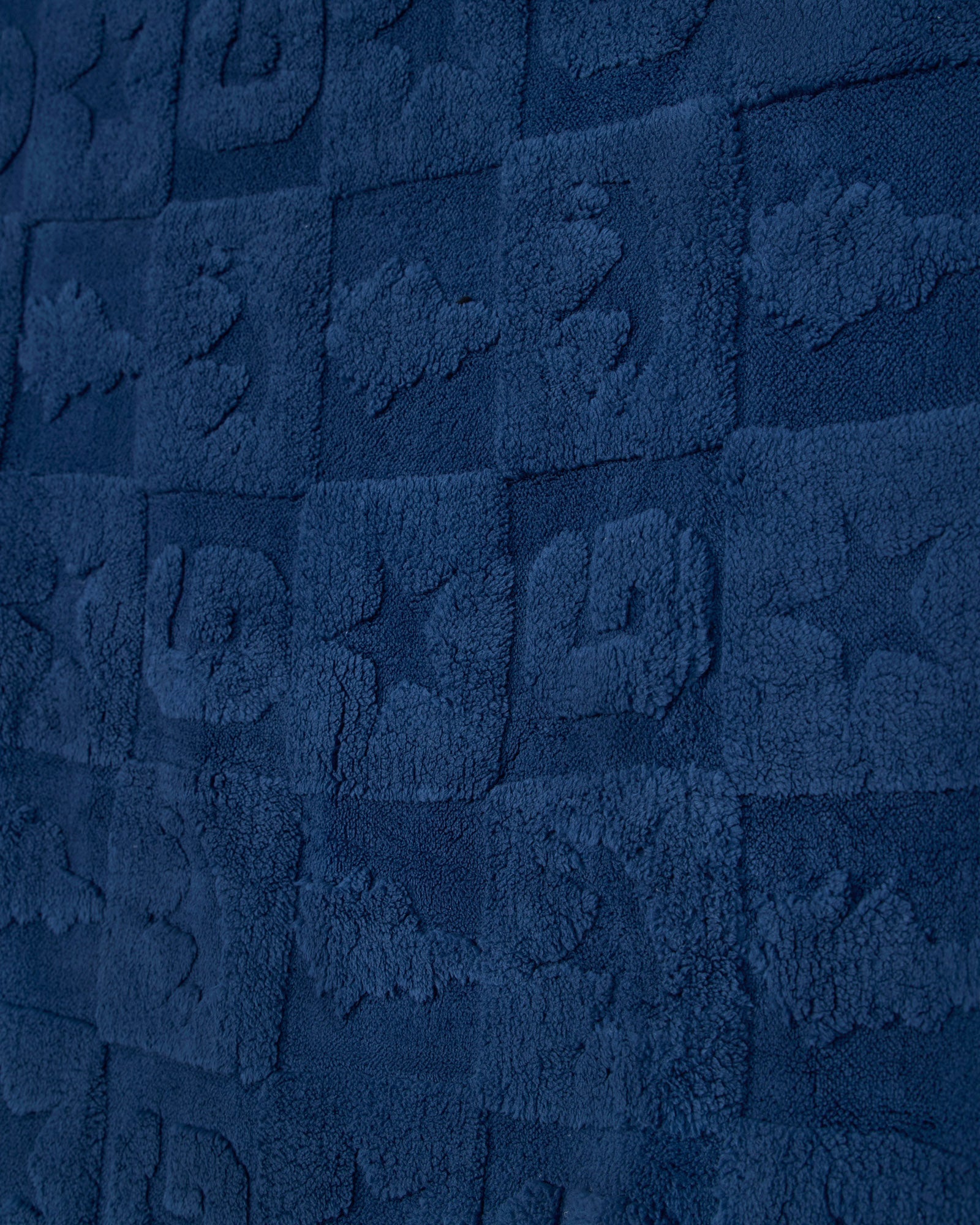 A close-up of a dark navy blue textured fabric with a repeating embossed block pattern.