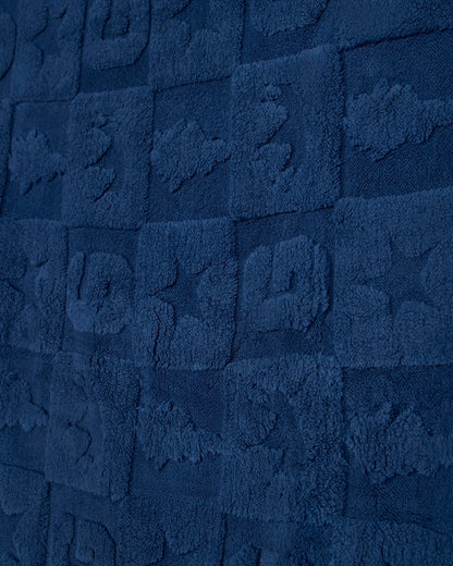 A close-up of a dark navy blue textured fabric with a repeating embossed block pattern.