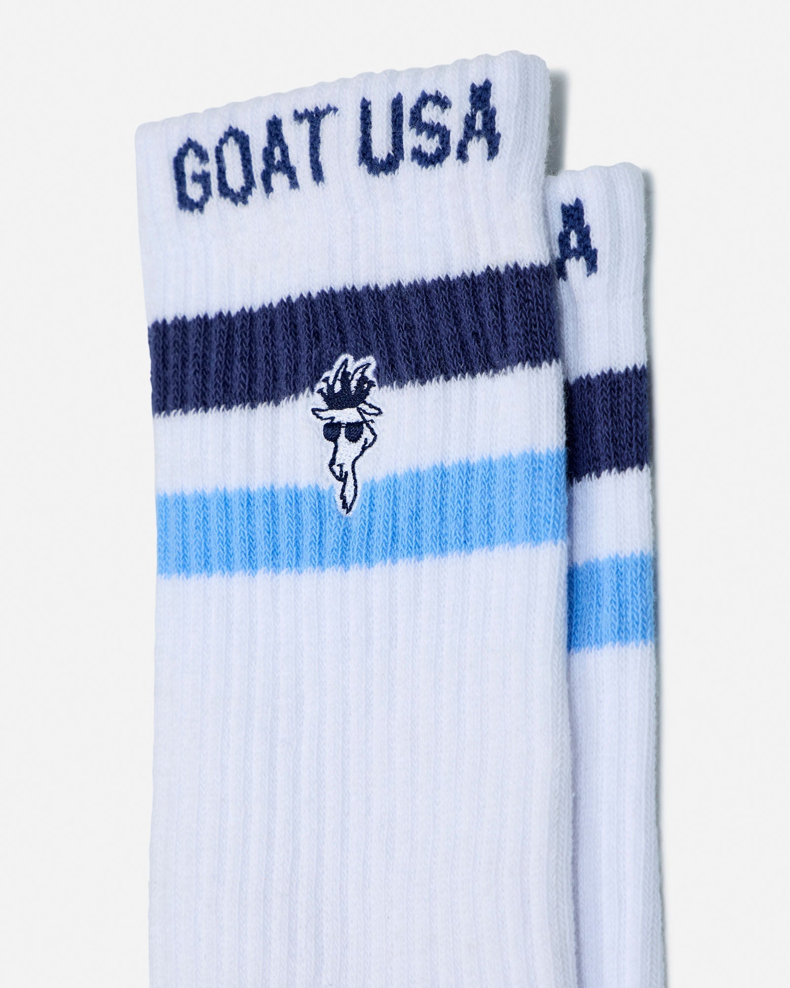 White socks with blue stripes and 'GOAT USA' text on a white background