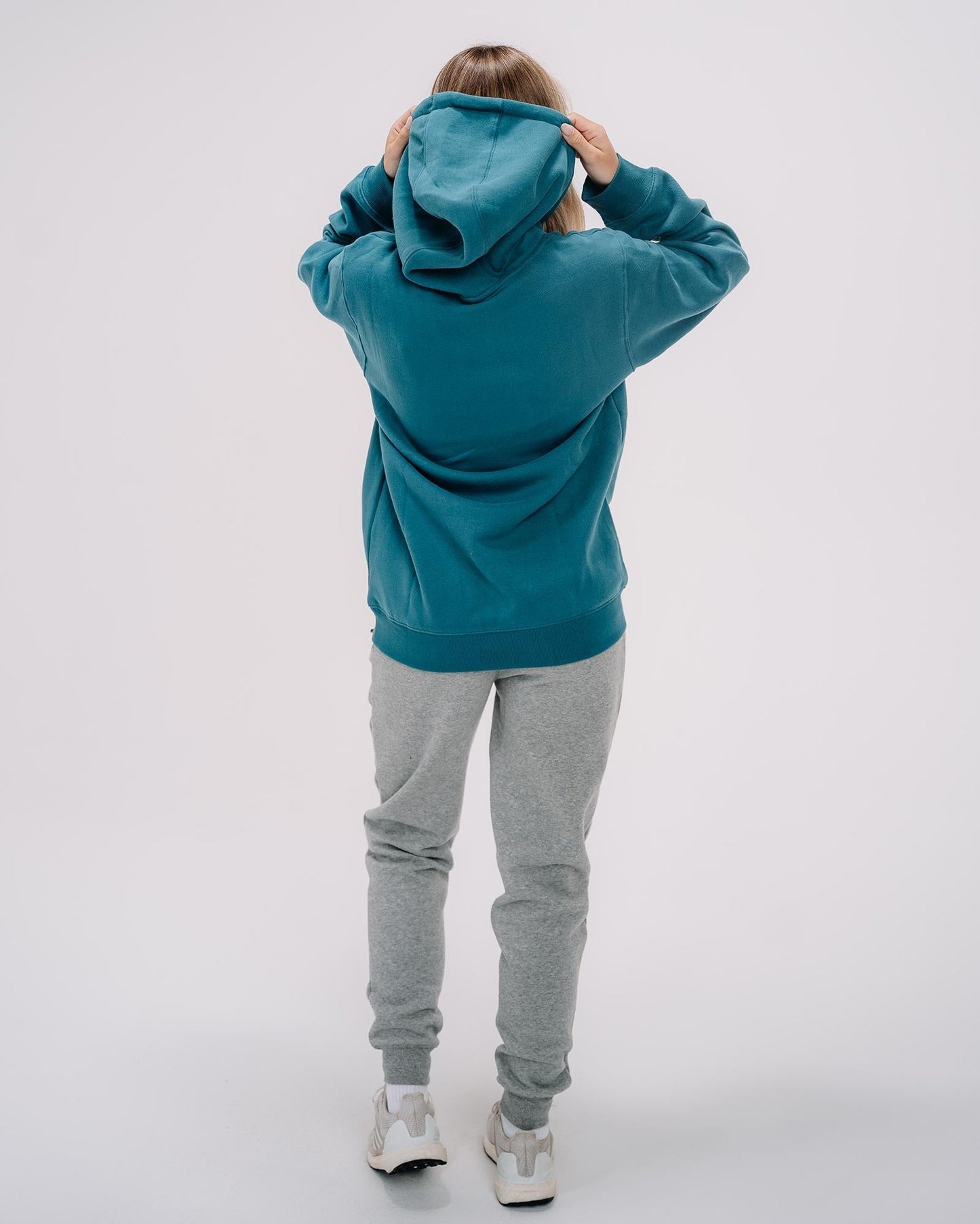 Back of female model wearing emerald WG Hooded Sweatshirt#color_emerald