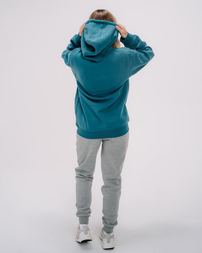 Back of female model wearing emerald WG Hooded Sweatshirt#color_emerald