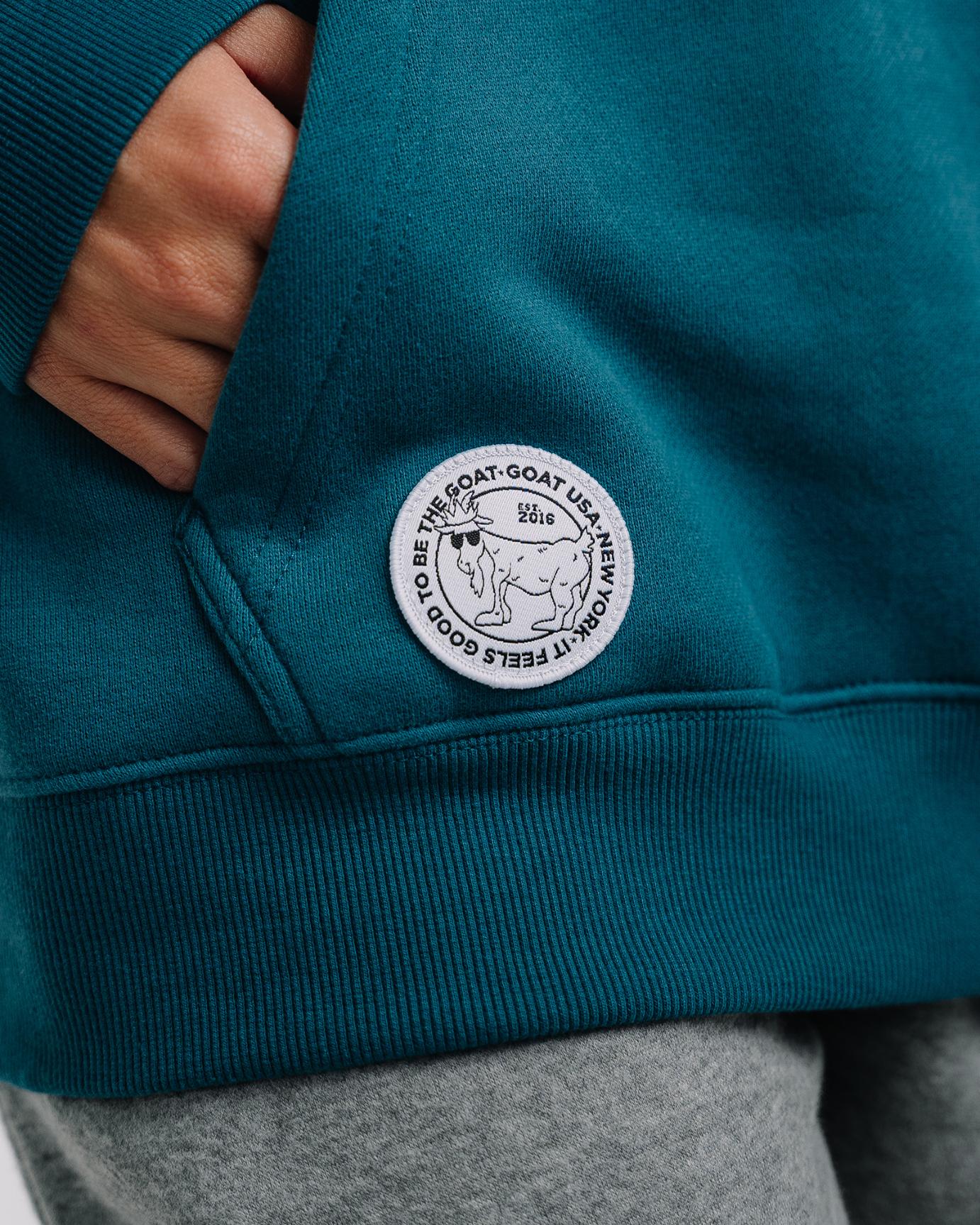 Close-up of patch on emerald WG Hooded Sweatshirt#color_emerald