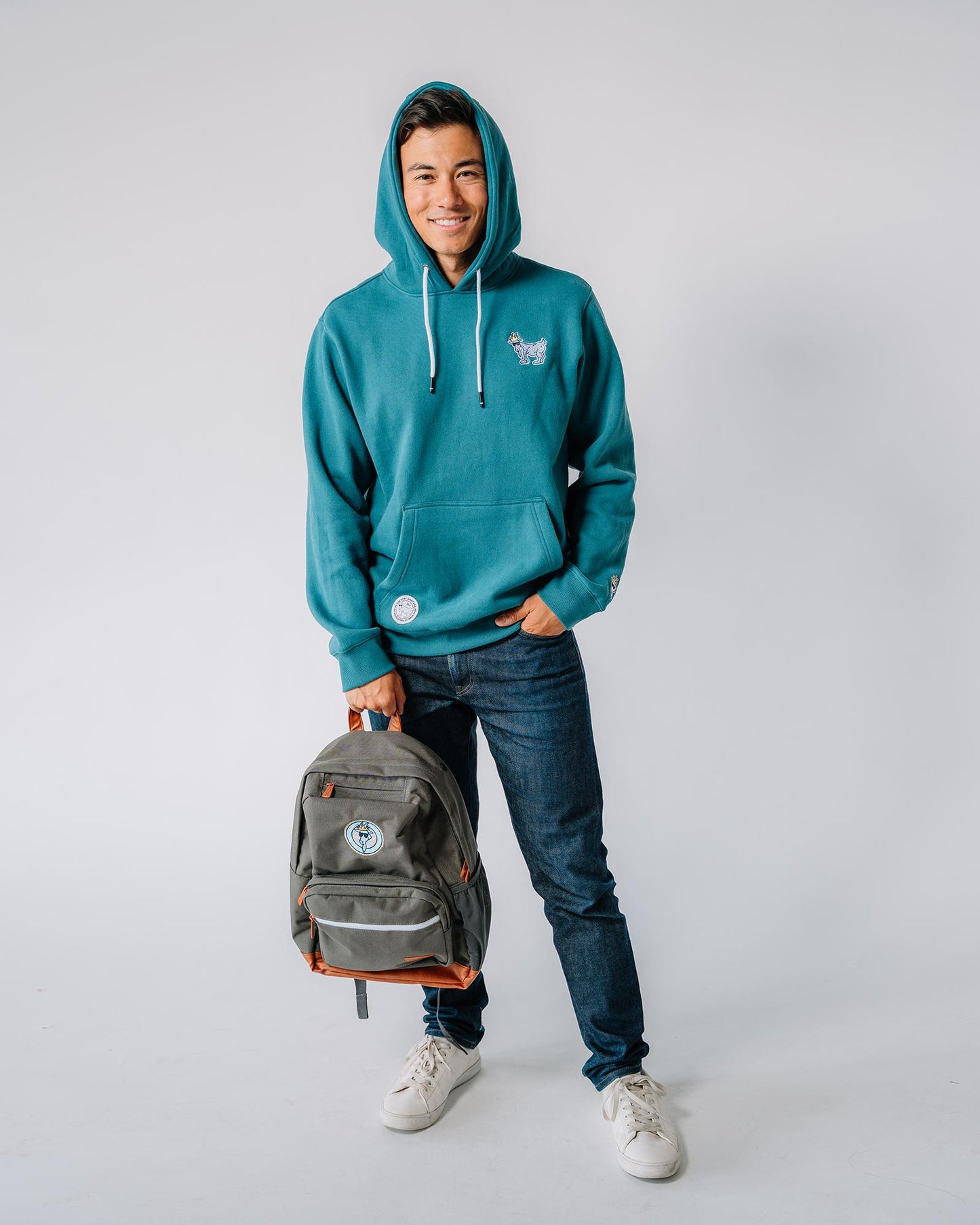 Male model holding backpack while wearing emerald WG Hooded Sweatshirt#color_emerald