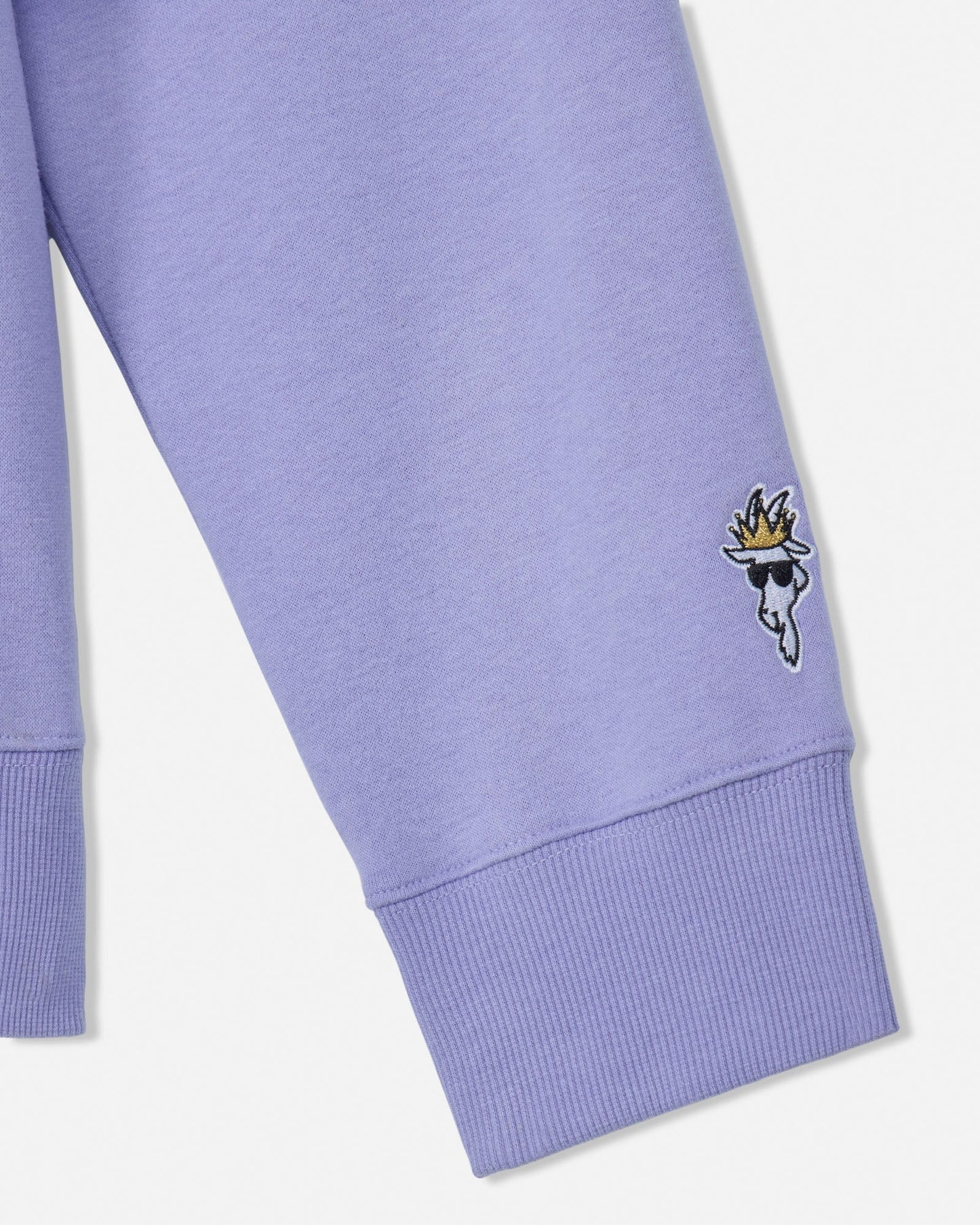 Close-up of a purple sweatshirt sleeve with a small embroidered design on a white background#color_periwinkle
