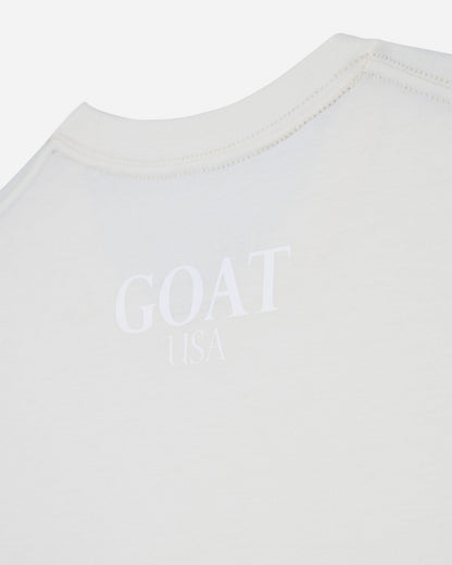 Close-up of a white crewneck t-shirt with a tonal, embossed 'GOAT USA' logo printed on the chest.#color_bone