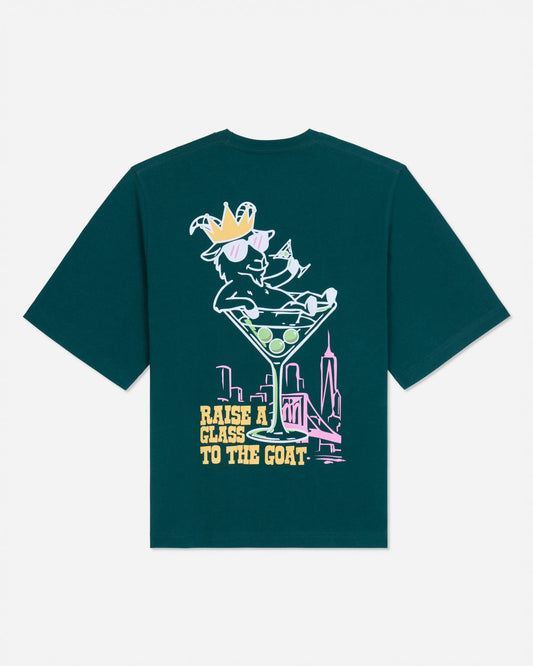 Back of sage t-shirt with martini glass goat graphic and text that reads 'Raise a glass to the GOAT'