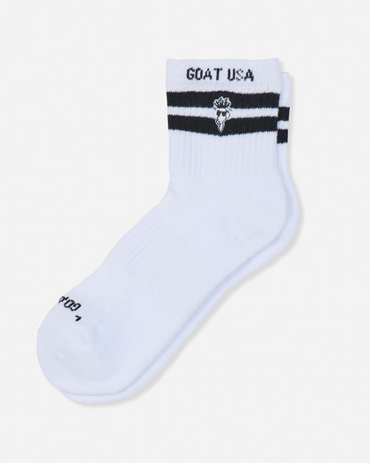 A single white crew sock with black stripes and 'GOAT USA' text on the cuff, displayed on a light gray background.#color_white