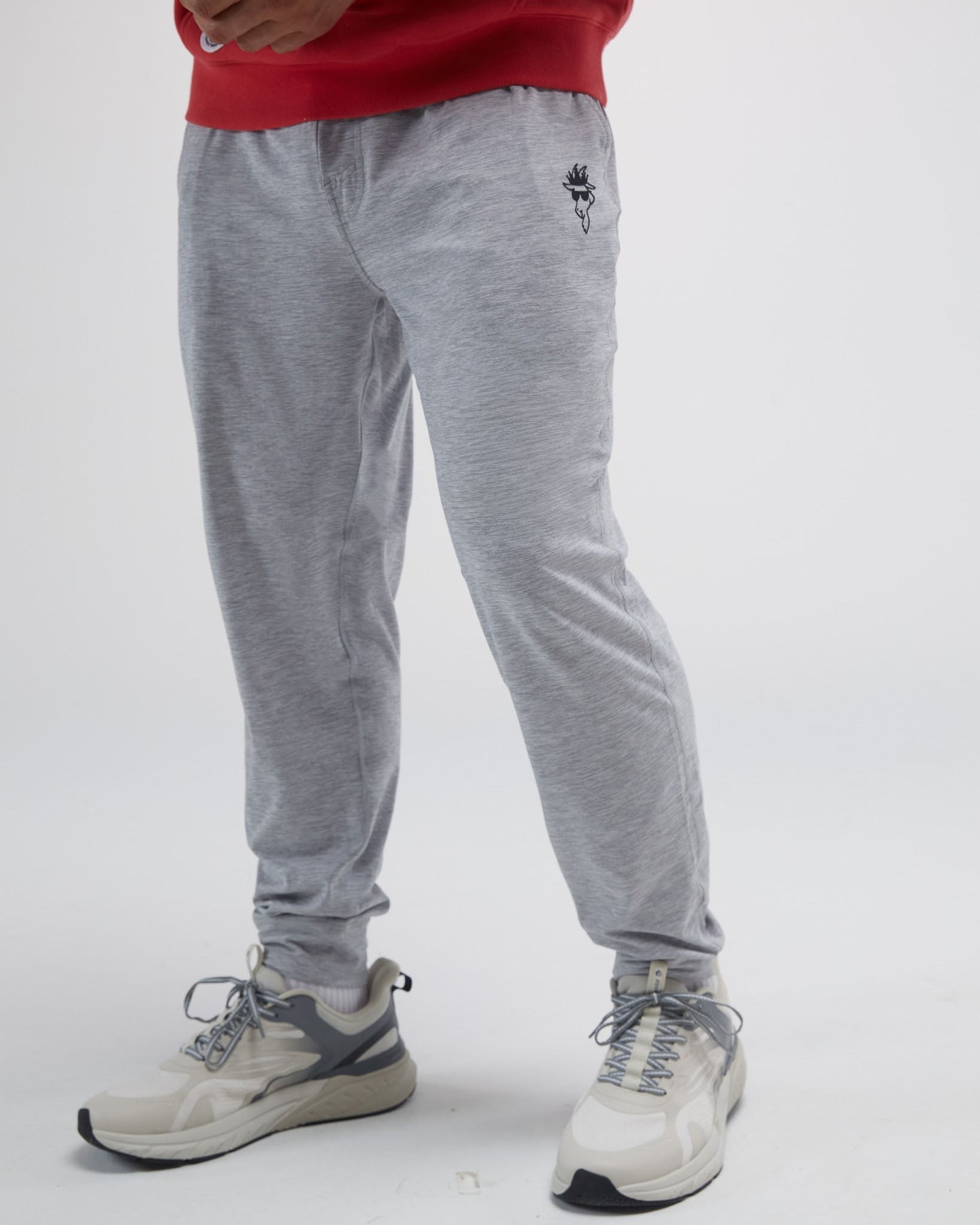 Person wearing gray jogger pants with a red top and white sneakers on a light gray background#color_space-dye-gray
