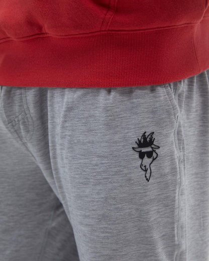 Gray sweatpants with a black embroidered design on the leg, worn with a red hoodie.#color_space-dye-gray