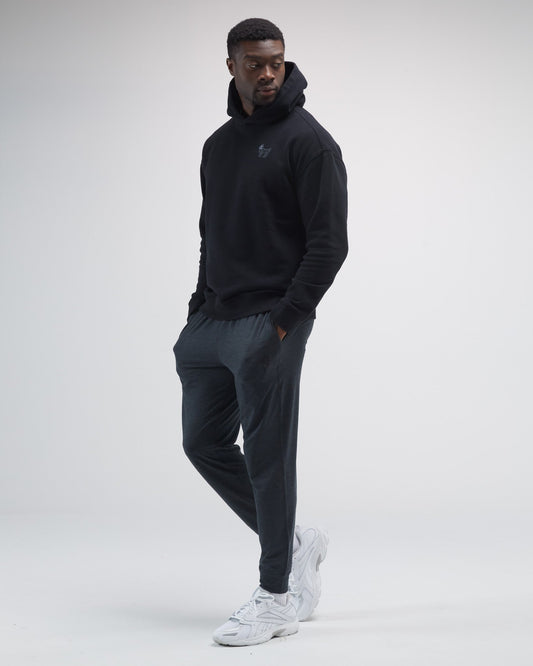 Man wearing a black hoodie and gray pants on a white background#space-dye-black