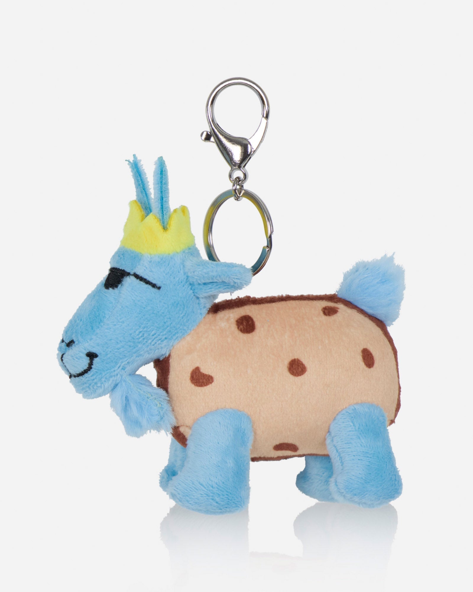 A plush goat bag charm styled like a cookie, featuring a light blue body, a beige body with brown spots, a yellow crown, and a silver metal clasp on a light gray background.
