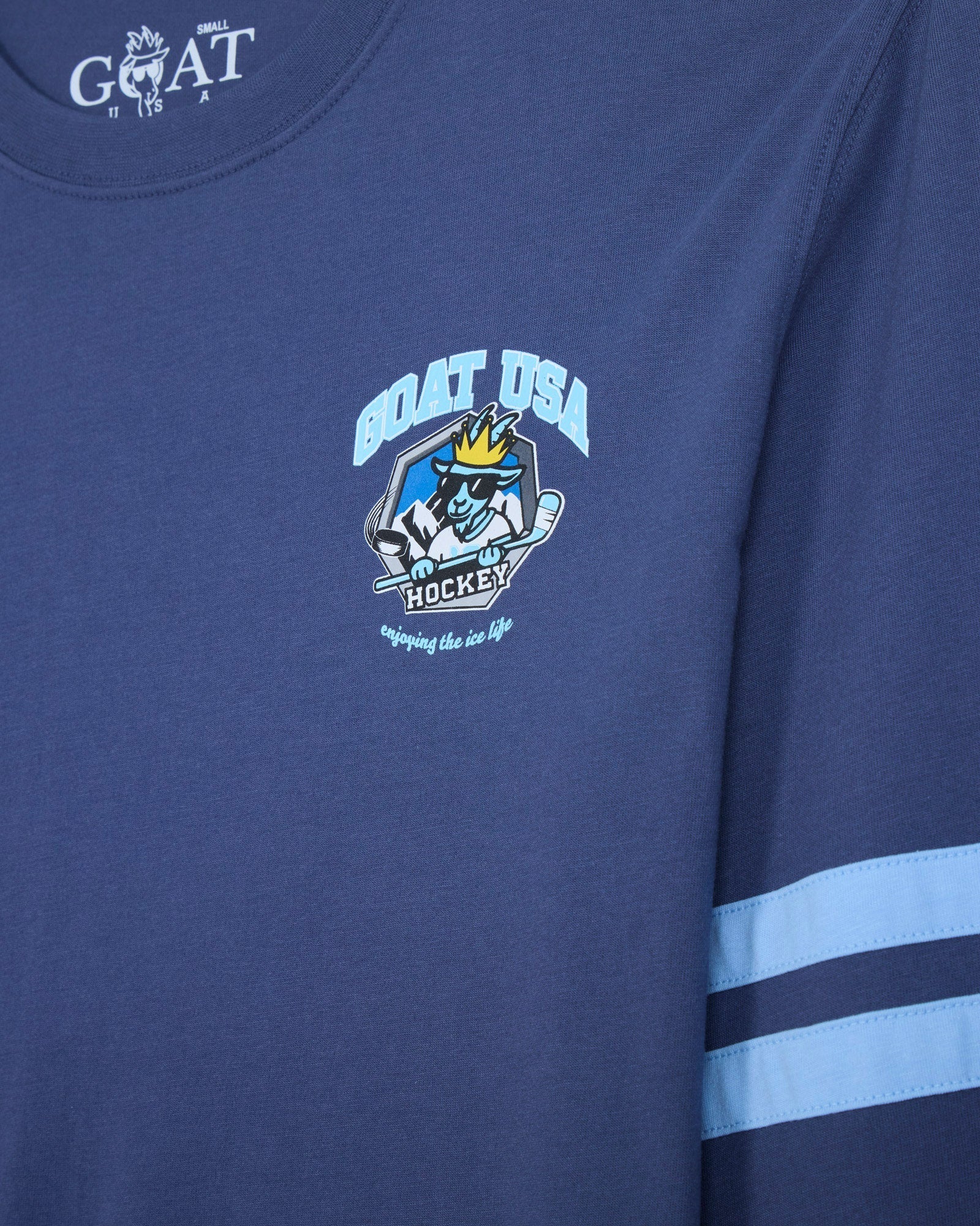 Close-up of a navy blue long-sleeve t-shirt with a light blue and white 'GOAT USA Ice Hockey' graphic on the chest and two light blue stripes on the sleeve.