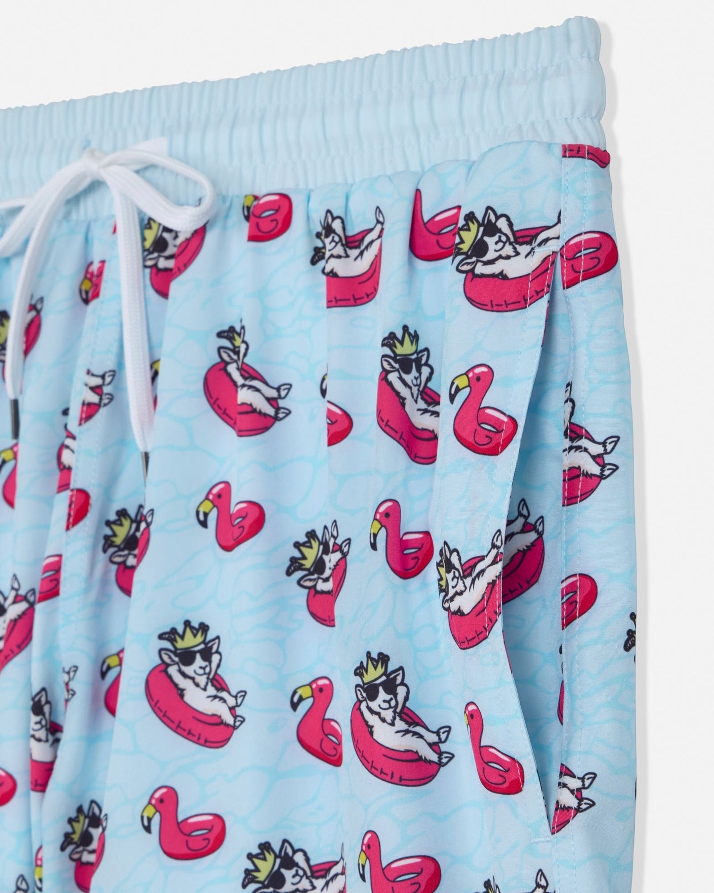 Light blue shorts with a cartoon goat design on flamingo pool floats.