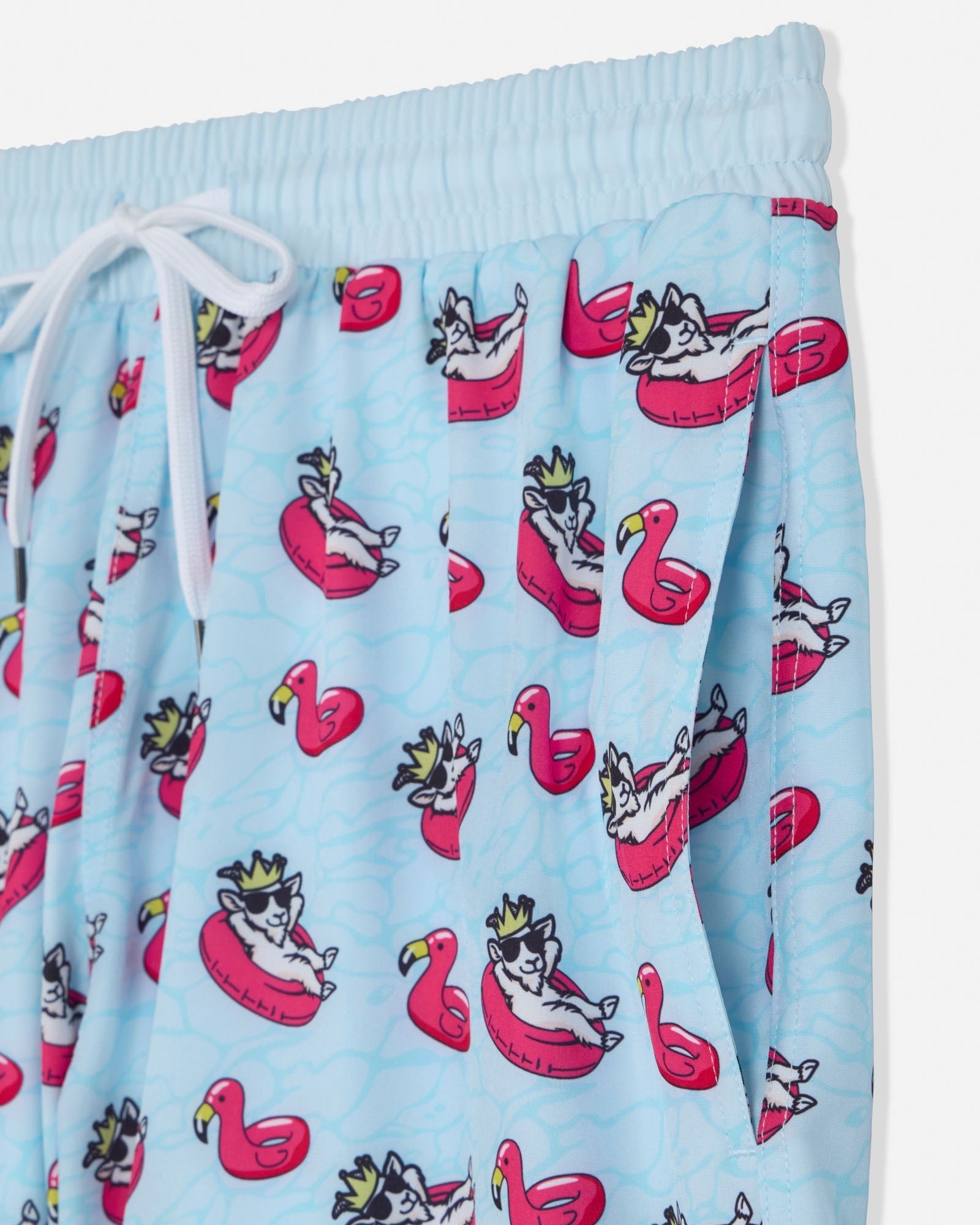Light blue shorts with a cartoon goat design on flamingo pool floats.