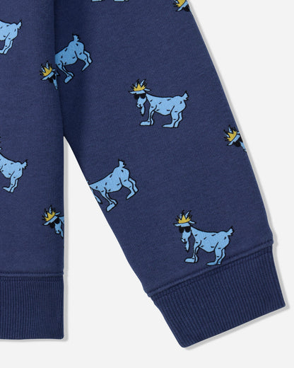 Close-up of a navy blue garment, likely a sweatshirt or pants leg, featuring an allover print of light blue goats wearing small yellow crowns, with ribbed cuffs at the bottom.#color_navy
