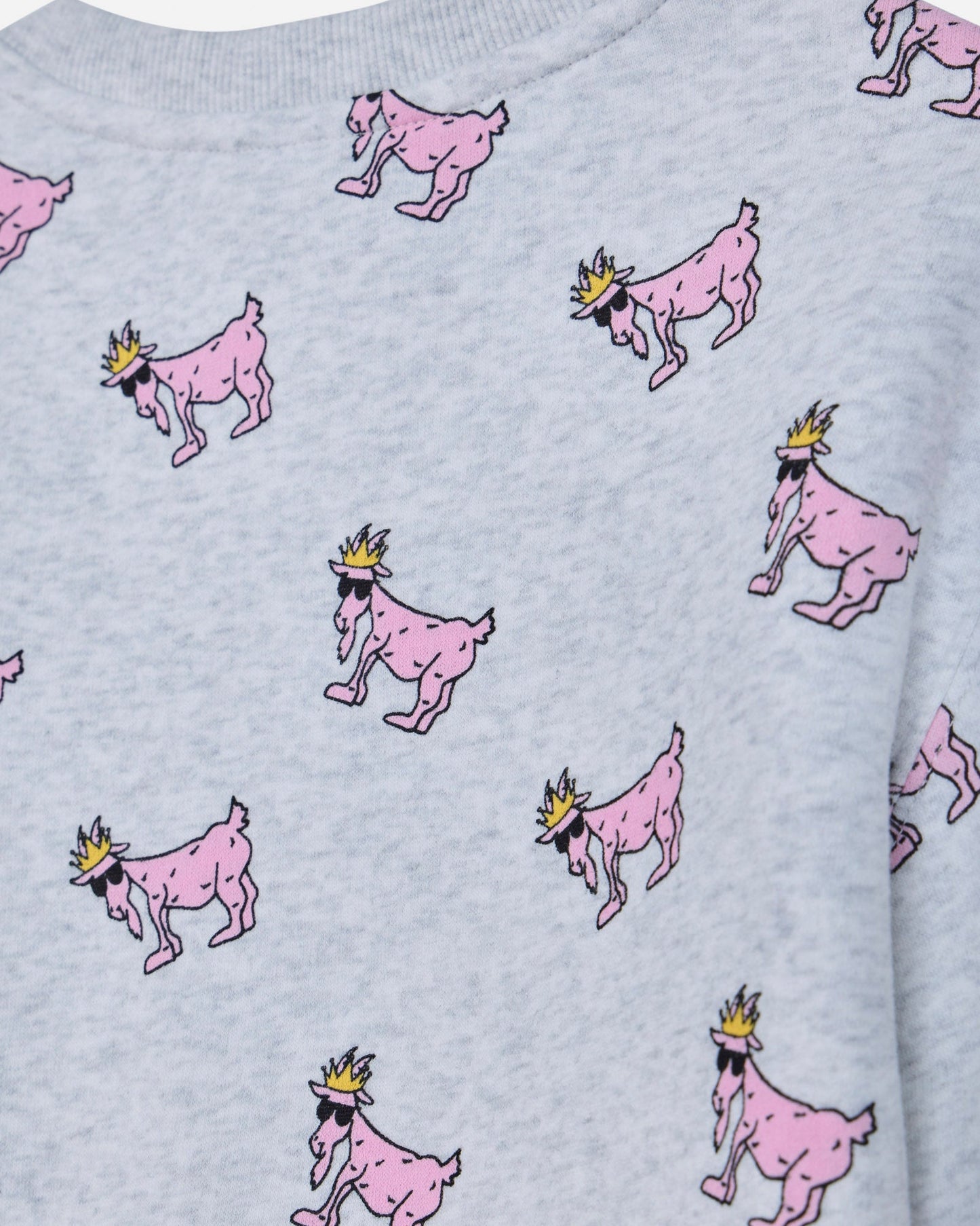 Close-up of a light gray heather sweatshirt featuring an all-over print of pink cartoon goats wearing small gold crowns.#color_pale-gray-heather