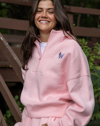 Person wearing a pink hoodie with a logo, standing outdoors.#color_pink