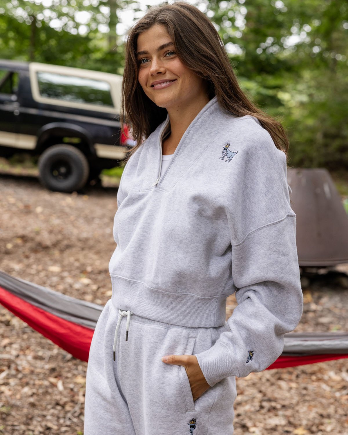 Person wearing a gray hoodie with a logo, standing outdoors.#color_pale-gray