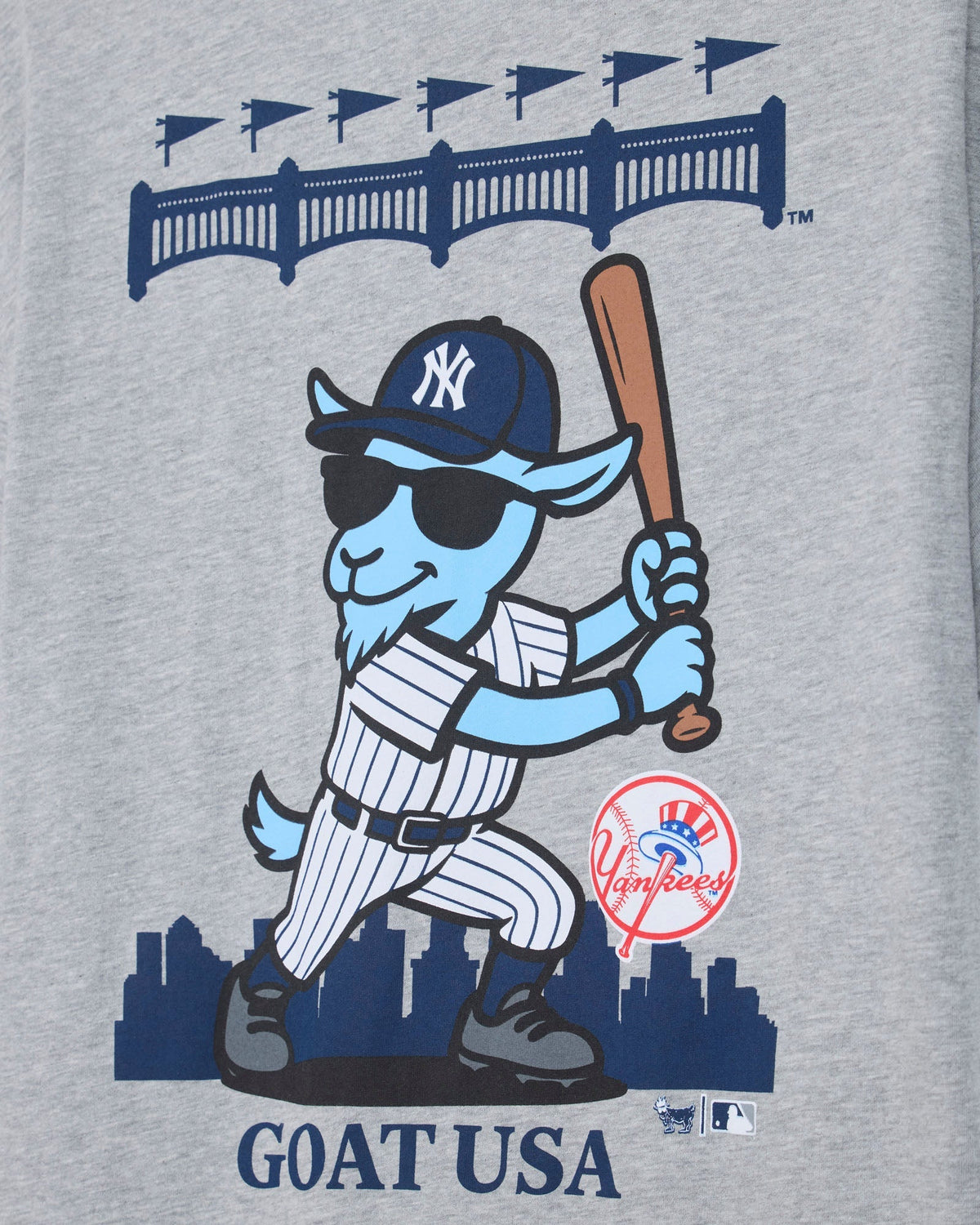 Close-up of a heather gray graphic print featuring a cartoon blue goat in a New York Yankees baseball uniform, holding a bat, with the text 'GOAT USA' and a Yankees logo.#color_gray