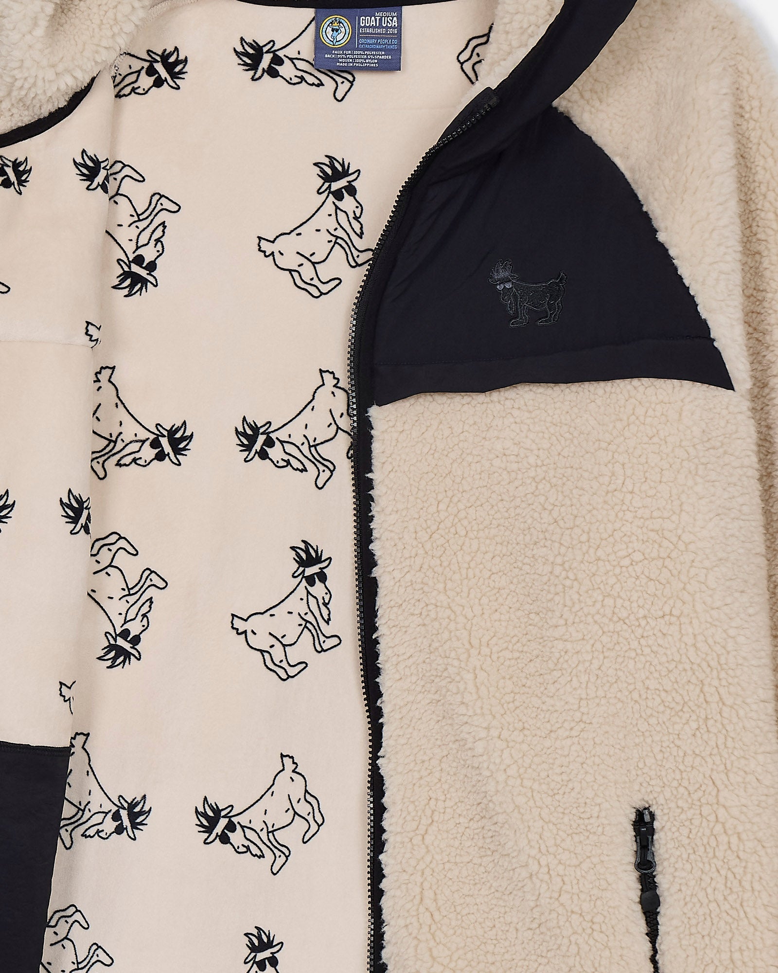 Close-up of a fleece jacket with goat pattern and visible brand label.#color_sandshell